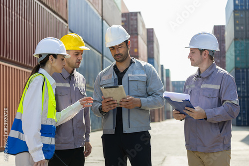 Engineers and dock workers reviewing logistics plan at cargo container yard, Team of industrial professionals discussing operations with digital tablet at port