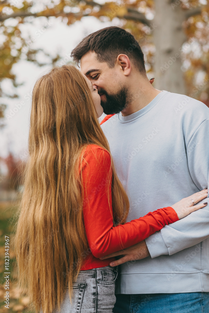 Obraz premium couple sharing tender forehead kiss, romantic portrait of lovers amid fall leaves with gentle light