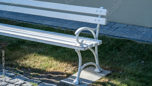 Fototapeta Naklejka Na Ścianę i Meble -  White wooden park bench on grass in sunlight