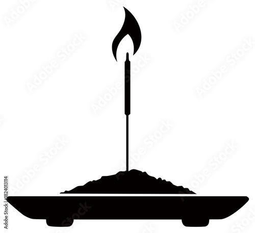 Silhouette of a burning incense stick with flame on a tray of sand