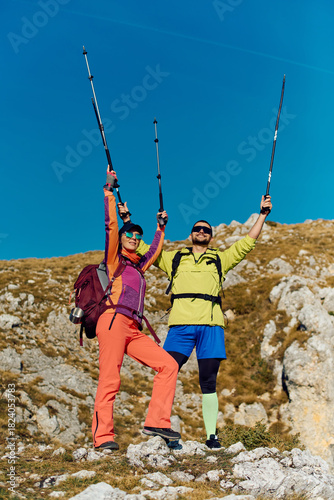 Happy hikers celebrate at the top of a rocky mountain during a sunny day in the wilderness