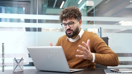 Angry businessman arguing talking on a video call using laptop computer sitting at workplace in business office. A nervous boss scolds and argues with a subordinate in an online conference meeting