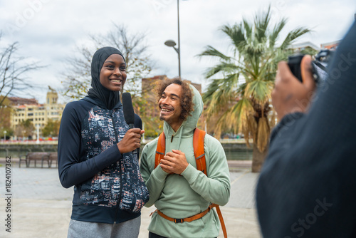 Female reporter interviewing smiling man in urban setting