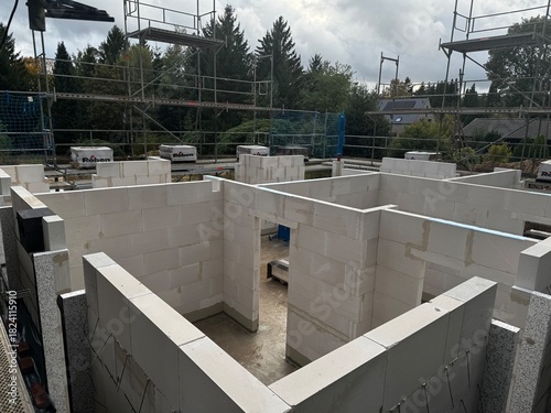 Ein Rohbau aus Porenbetonsteinen auf einer Baustelle mit Gerüst und Baumaterialien
