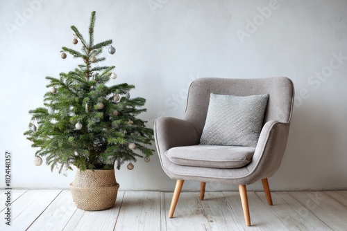 Small evergreen holiday tree sits beside a comfortable upholstered armchair in a bright room