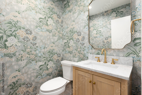 фотографія A half bathroom with a marble countertop on a white oak cabinet, gold faucet and mirror, and a green floral wallpaper