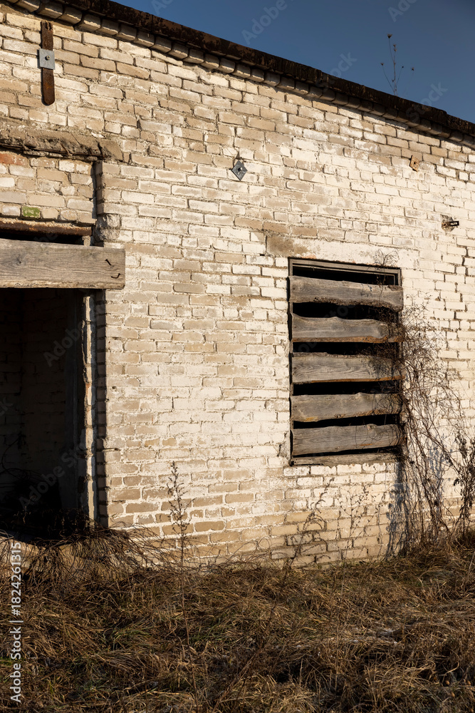Fototapeta premium an abandoned building made of brick in the winter, an abandoned building intended for demolition, the entrances and windows to the building are boarded up