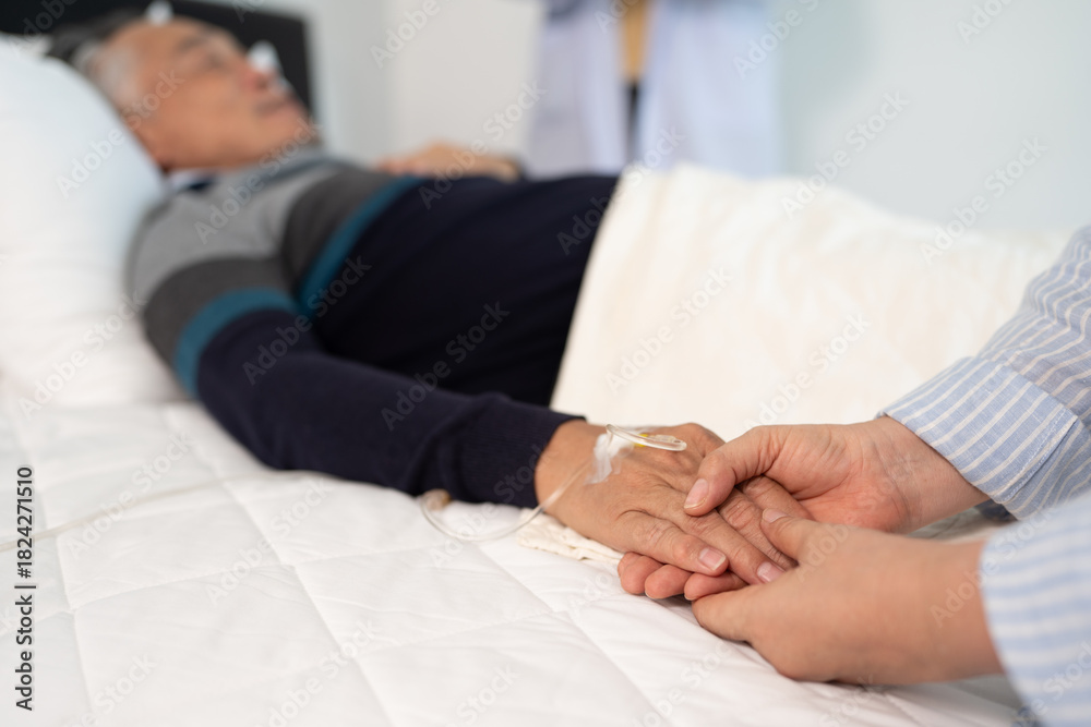 Fototapeta premium scene of bedridden patient, focus on hand of wife holding hands illness elderly hopeless senior man. home caregiver nurse visit retirement patient for health check up recovery process medical service
