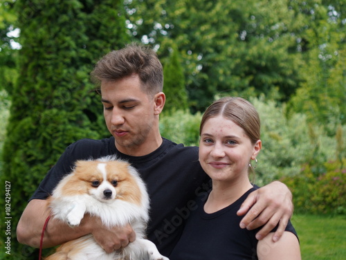 couple with dog, young  man with girl and with pomeranian spitz in the park portrait