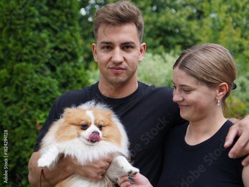 couple with dog, young  man with girl and with pomeranian spitz in the park portrait