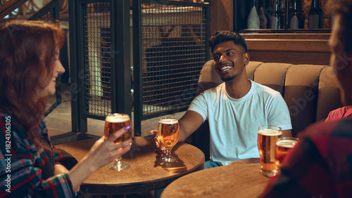 Quadro su tela Friends chatting with beer glasses at wooden pub table