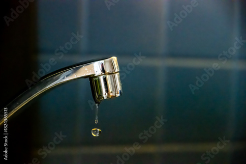 Precious water slowly dripping from a leaky faucet