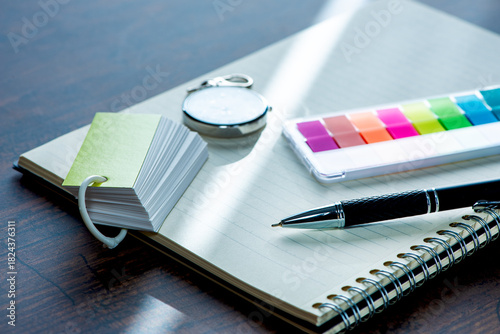 机の上のノートとペンと時計