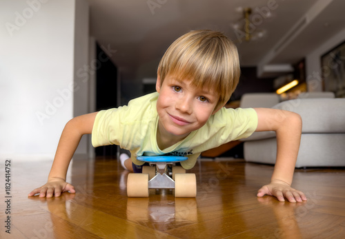 Smiling blond boy of 6 years old playing on a scooter at home.