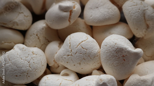Textured teardrop meringues with cracked sweet crust close-up, homemade sweet pastry made from egg white and sugar, textured light background of sweet snack
