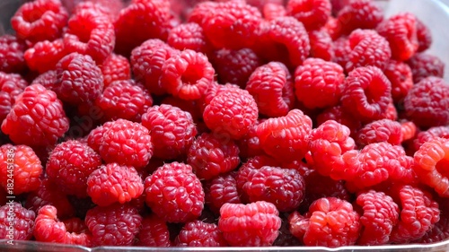 handful of fresh raspberries lying in a container, red ripe berries containing vitamins, with a wonderful aroma, raspberries for sale at the market, a tray with berries close-up, raspberry background