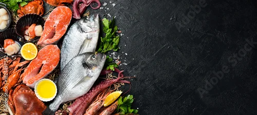 Obraz  z motywem Black slate stone background with seafood. Fish, clams, scallops, octopus, lobster and other seafood on the table. Free copy space.
