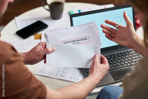 Slika na platnu Caucasian young adult man holding eviction notice envelope while sitting at desk