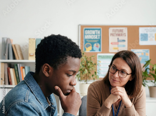 Teenage boy talking to school counselor in office mental health education support guidance youth problem depression psychology trust conversation student and teacher help advice sitting desk