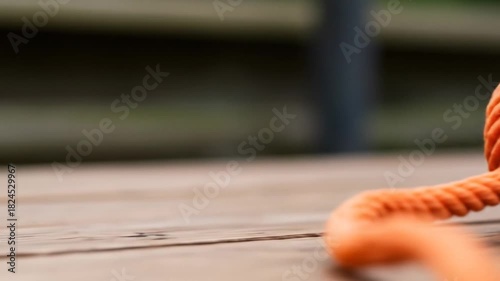 Closeup of orange rope coiled on a wooden surface