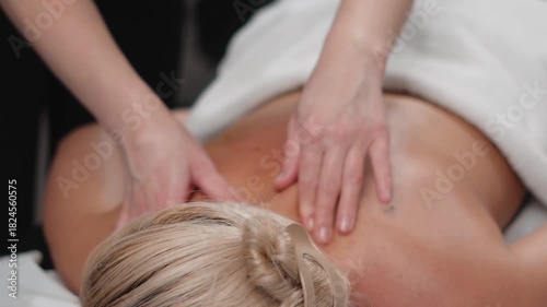Hands perform gentle back and neck techniques for a woman in a peaceful beauty spa