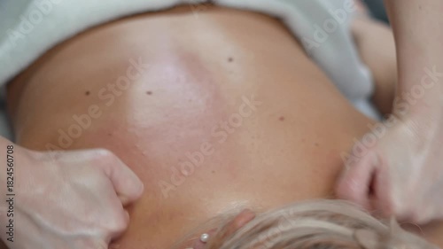 Hands perform gentle back and neck techniques for a woman in a peaceful beauty spa