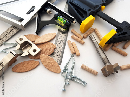 Composition of useful tools and accessories for furniture production. Contains screws, bolts, carpentry clamp, rulers and squares