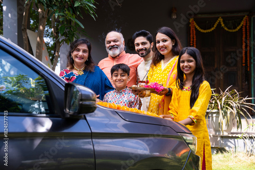 Indian family performing car puja ceremony to welcome their new vehicle with blessings