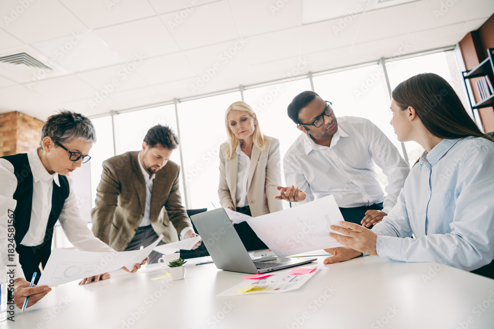 Obraz premium Professionally diverse team collaborating on project ideas in a modern office space with visuals and technology.