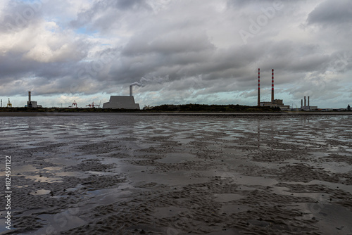 Reflective Tidal Flats and Mud Against Industrial Port and City Skyline