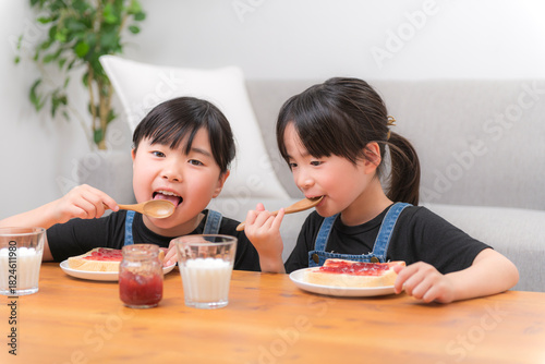 食パンにジャムをのせて食べる子どもたちの家庭的な朝の時間