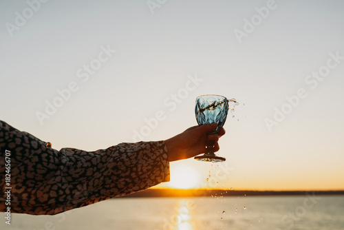 Wine Glass in Hand Against Sunset Sky and Sea – Toasting to Beauty and Freedom