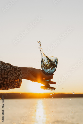 Wine Glass in Hand Against Sunset Sky and Sea – Toasting to Beauty and Freedom