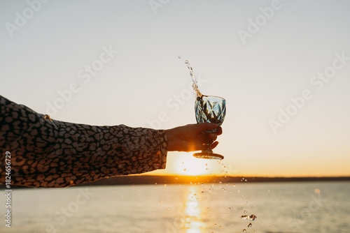 Wine Glass in Hand Against Sunset Sky and Sea – Toasting to Beauty and Freedom