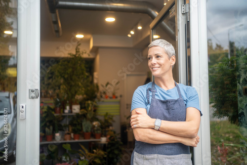 Foto Mature pretty woman working as florist in shop and smiling
