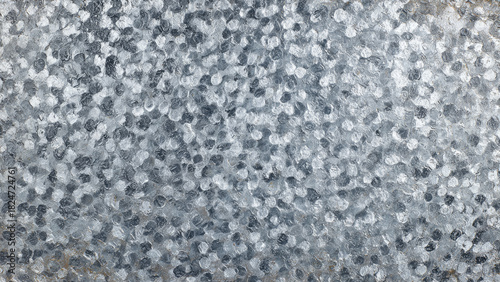 Close-up of a galvanized metal surface with a distinct spangled pattern. The textured background features silvery-gray, reflective crystalline flakes.