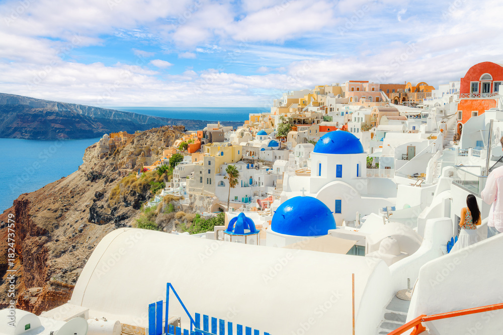 Obraz premium The famous blue dome churches highlight the whitewashed village of Oia, Greece, with the Aegean Sea in view on the island of Santorini.