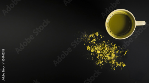 Top view of matcha tea with scattered powder on a black background.