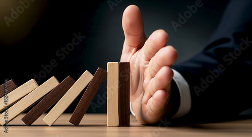Close up of a person s hand stopping a line of falling dominoes symbolizing risk management prevention and crisis intervention in business and life
