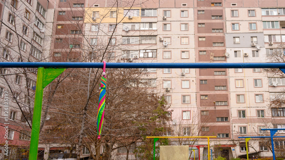 Obraz premium bright rainbow umbrella hangs on a blue-green bar in a house courtyard
