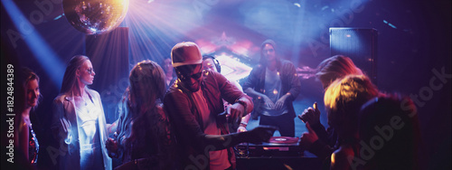 Obraz na płótnie Party atmosphere in a club with a DJ, vibrant lights, and dancing guests during