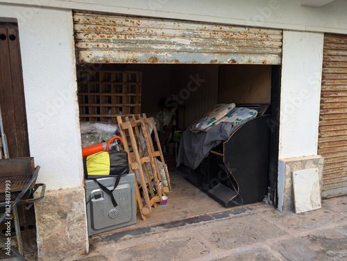 Quadro su tela Garage entrance converted into storage room unit with junk, discarded appliances, furniture and rusted roller shutter