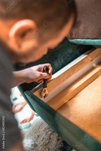 Canvas Print Man disassembling sofa furniture mechanism at home using furniture wrench