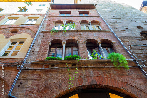 Old Brick Building With Ivy And Arched Windows On Narrow European City Street