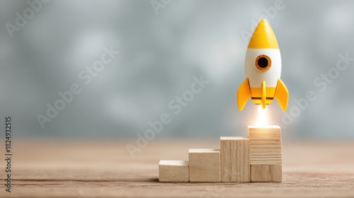 A small rocket launches from a stack of wooden blocks, symbolizing progress and ambition. The soft background adds to the inspirational atmosphere, perfect for creative initiatives.