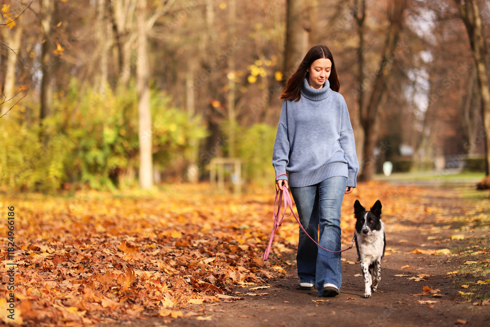 Naklejka premium Woman walking her cute dog in autumn park, space for text