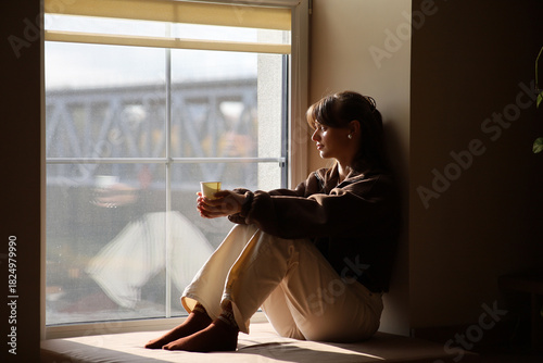 Pensive woman enjoying a quiet moment by the window with a warm drink