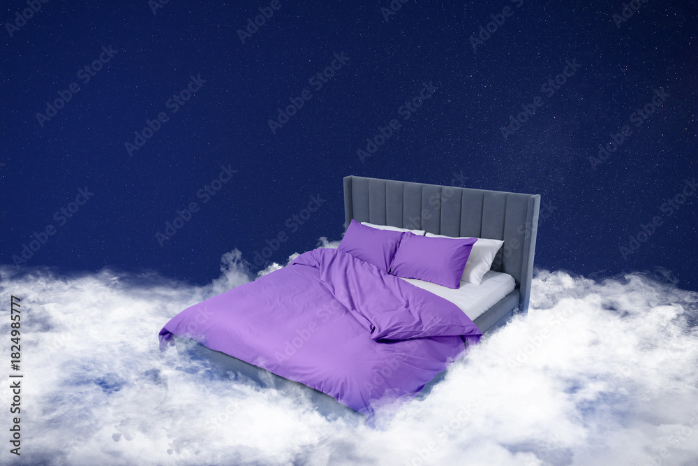 Fototapeta premium Large bed on fluffy clouds in starry night sky