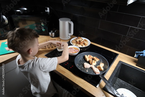 Bilde på lerret Young boy helping prepare food at home kitchen
