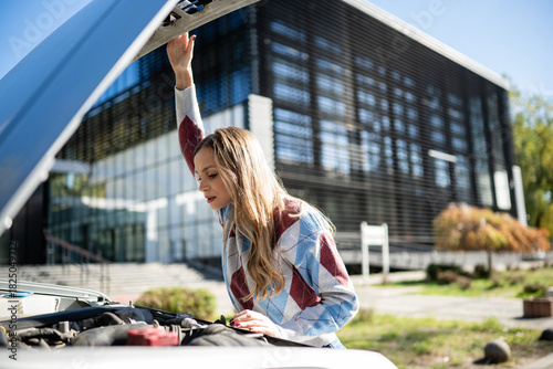 Billede på lærred Woman examining broken down car engine problem